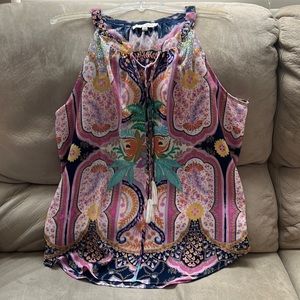 Light and airy colorful print sleeveless top. It ties at collar and has tassels